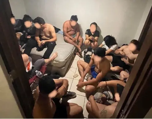 A group of migrants in a small room with faces blurred