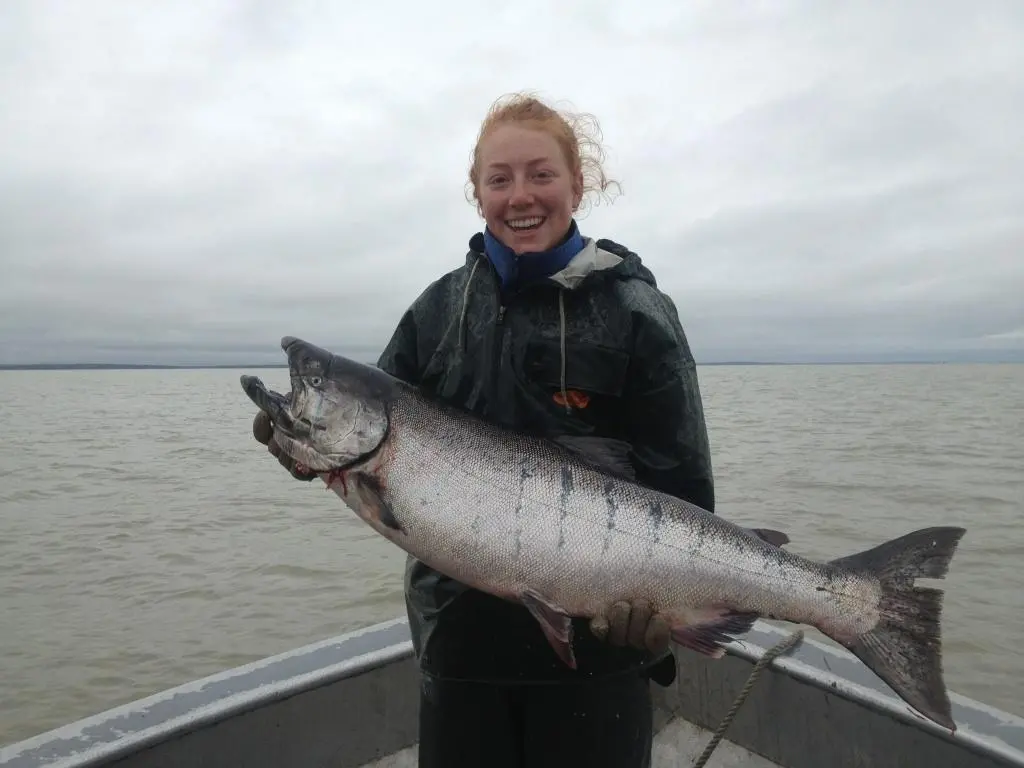 Elma Burnham holds a large king salmon on a boat.