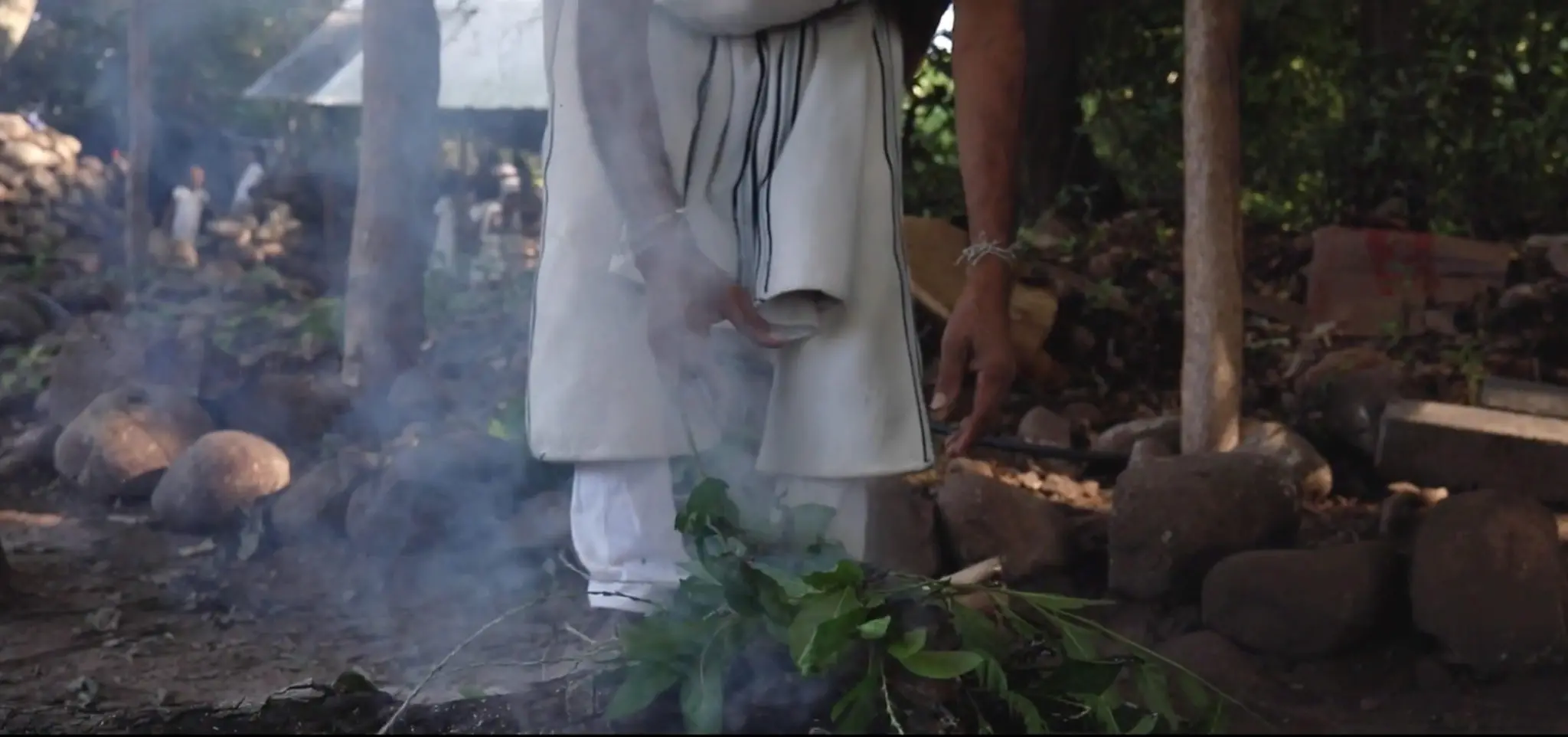 A Indigenous person works over fire