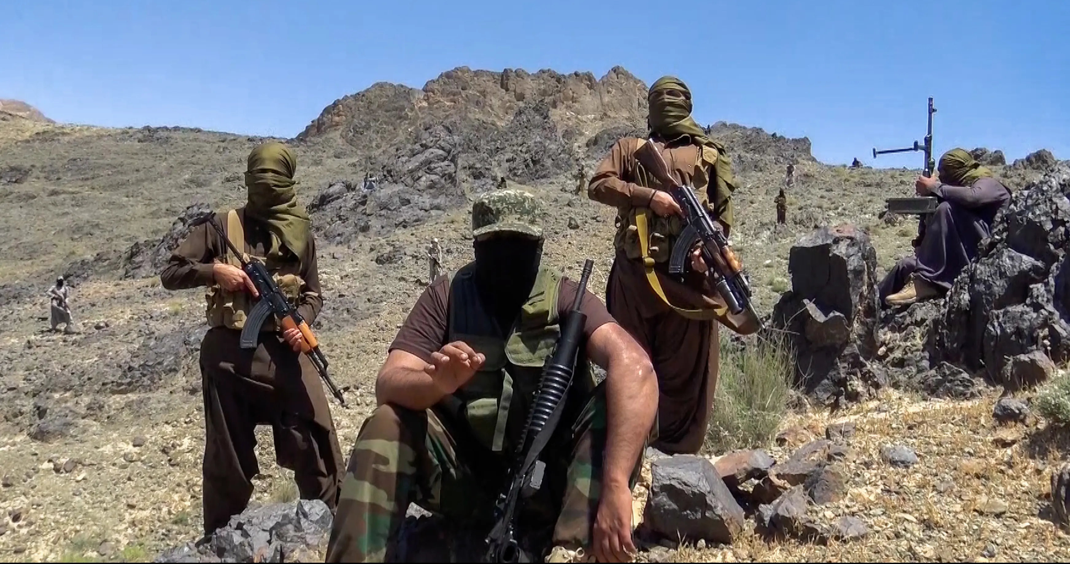 People with guns stand on a mountain.