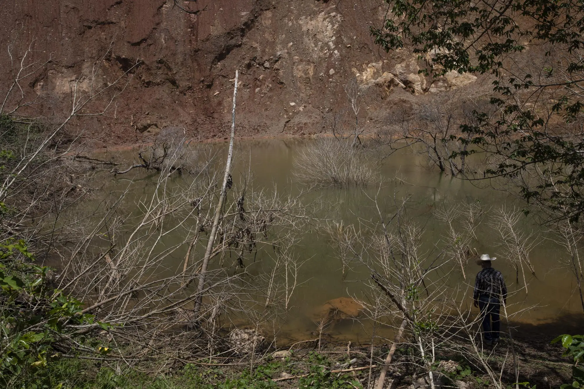Man stands by lagoon that formed after mudslide