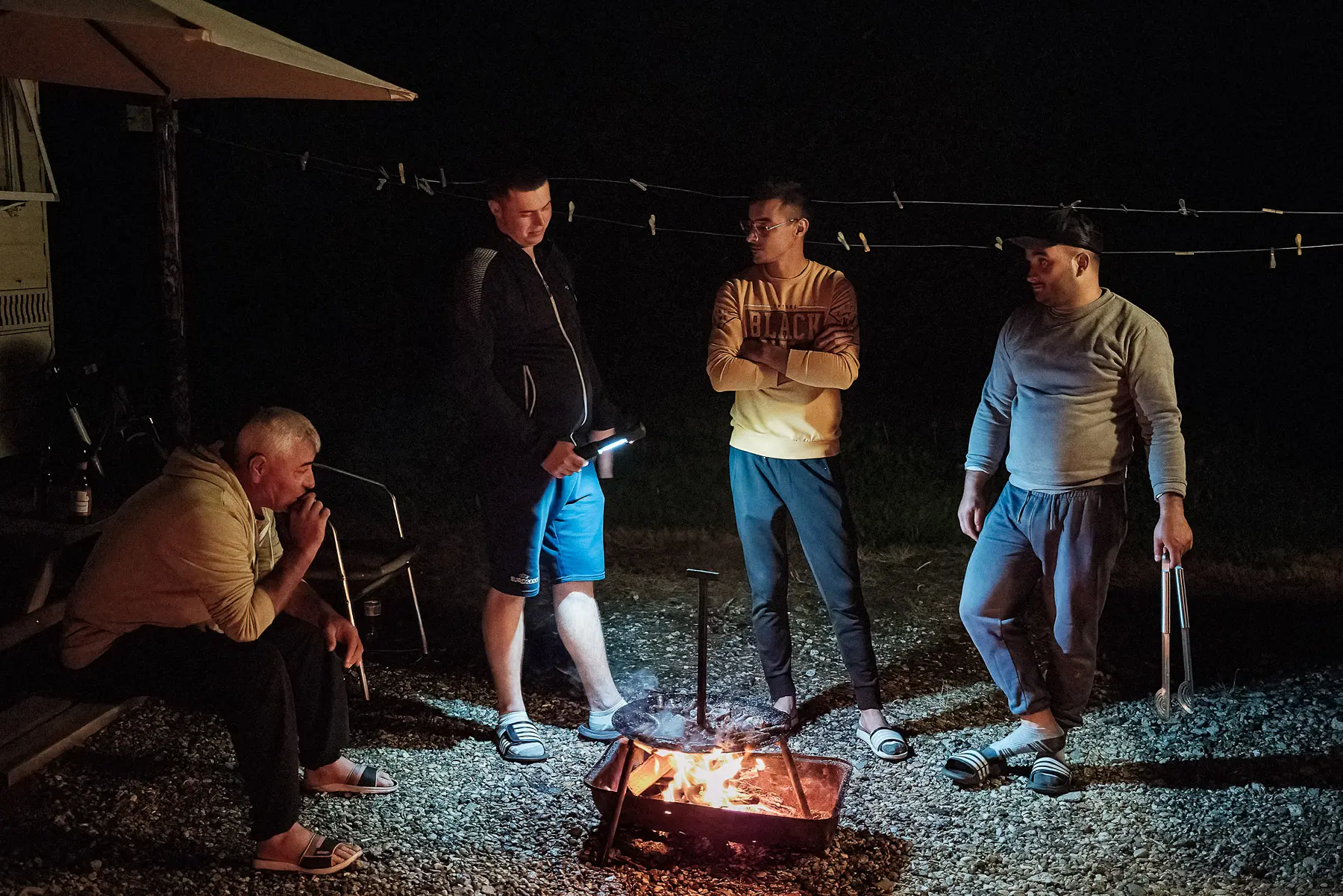 Four Romanian workers fry sausages on a disk at night