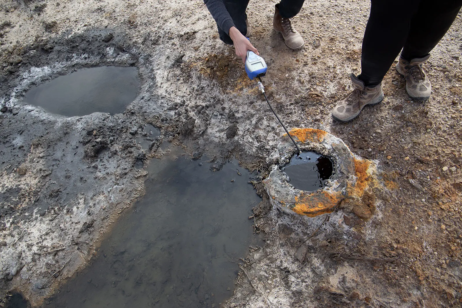 People measure a well using a small device.