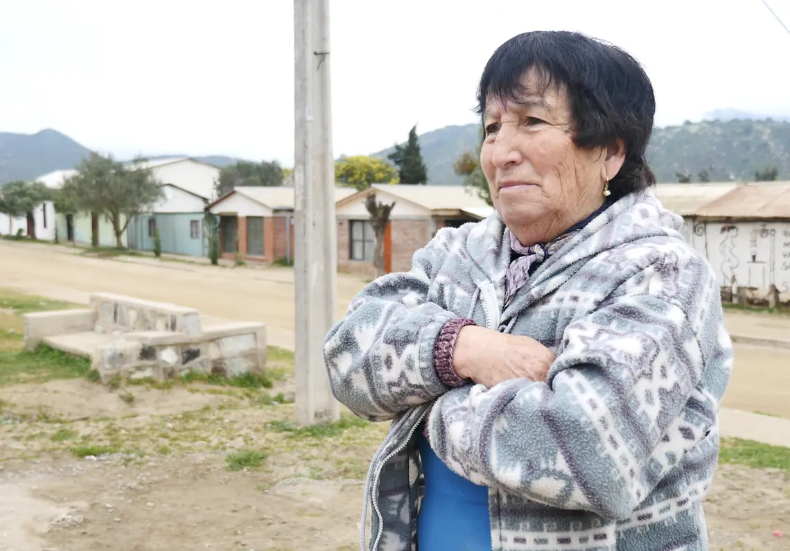 Woman stands in front of village