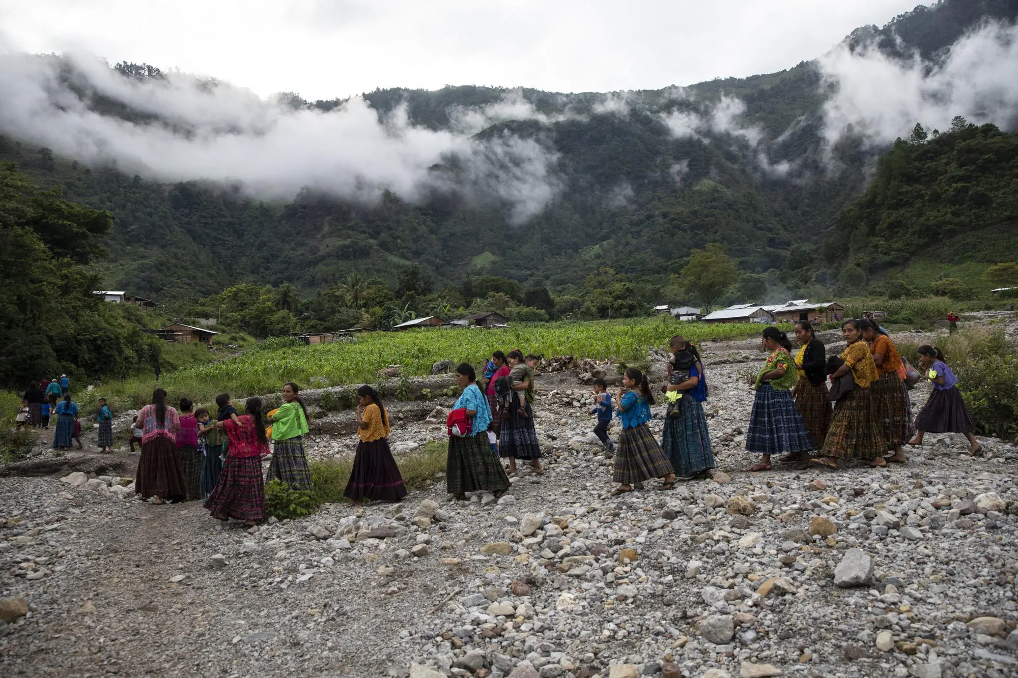 Women walk to a meeting across rocks after attending a mass