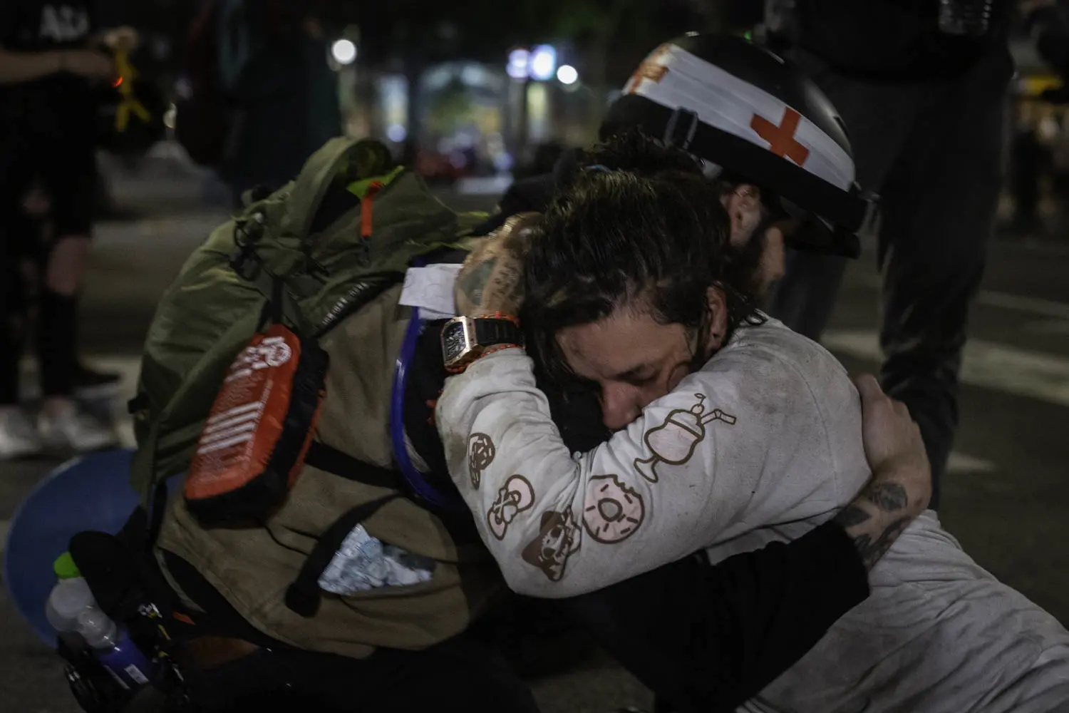 A medic embraces someone who has collapsed in the street.