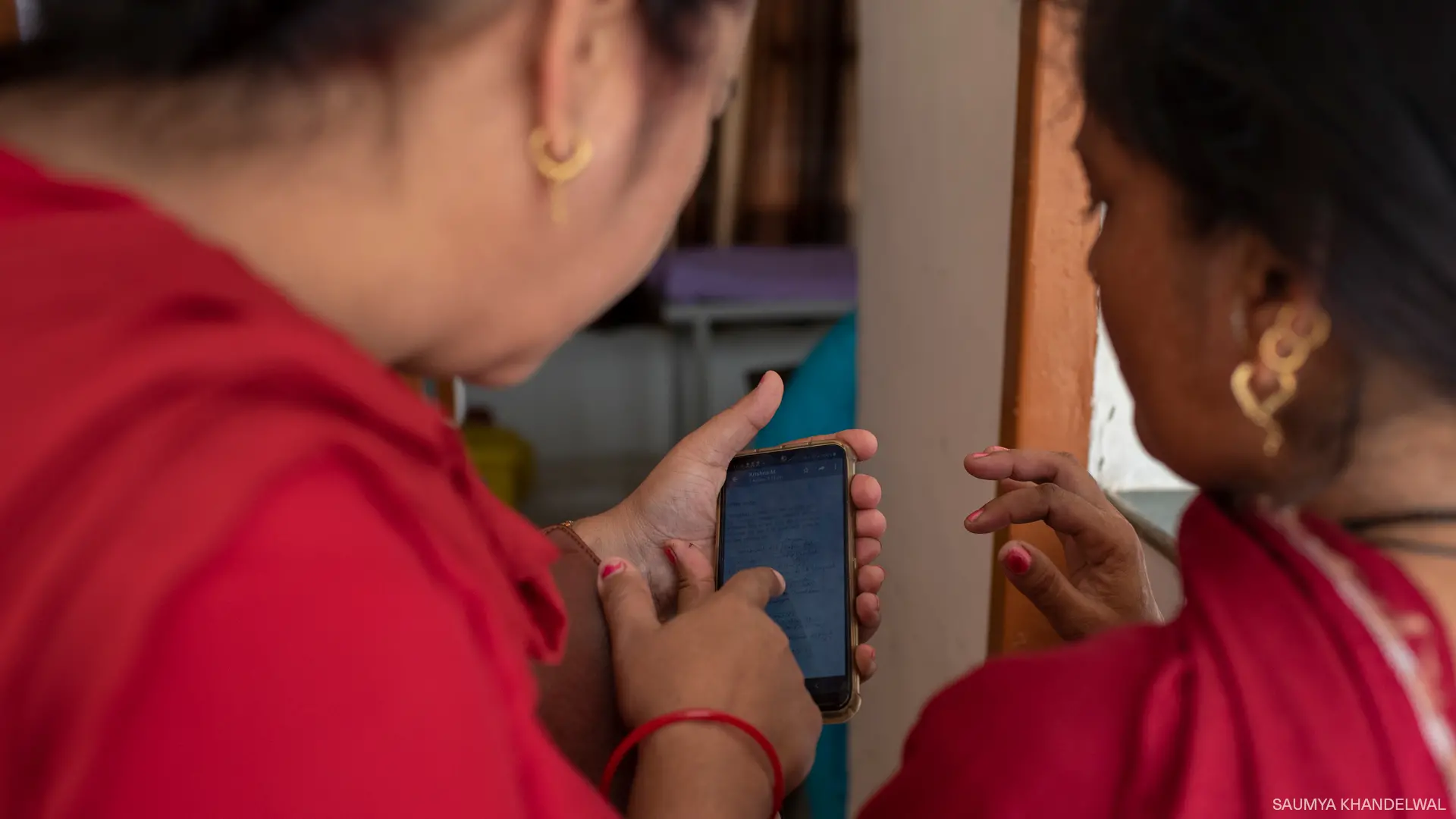 Woman shows another woman how to use an app on her phone