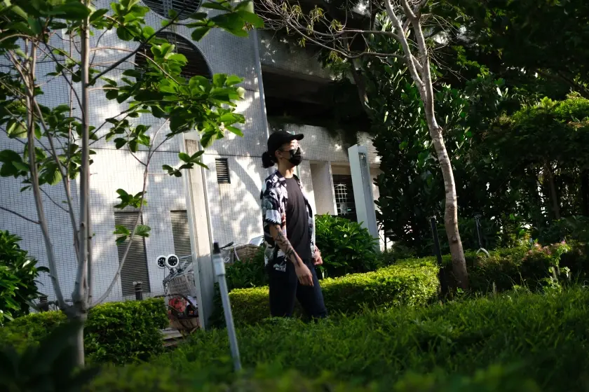 A man stands center-frame in an off-tilt scene of urban landscaping.