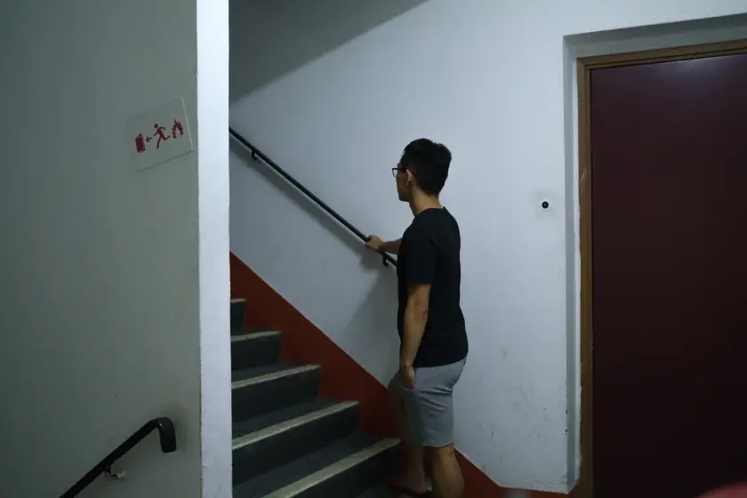 A man holds a rail at the base of a second flight of stairs.