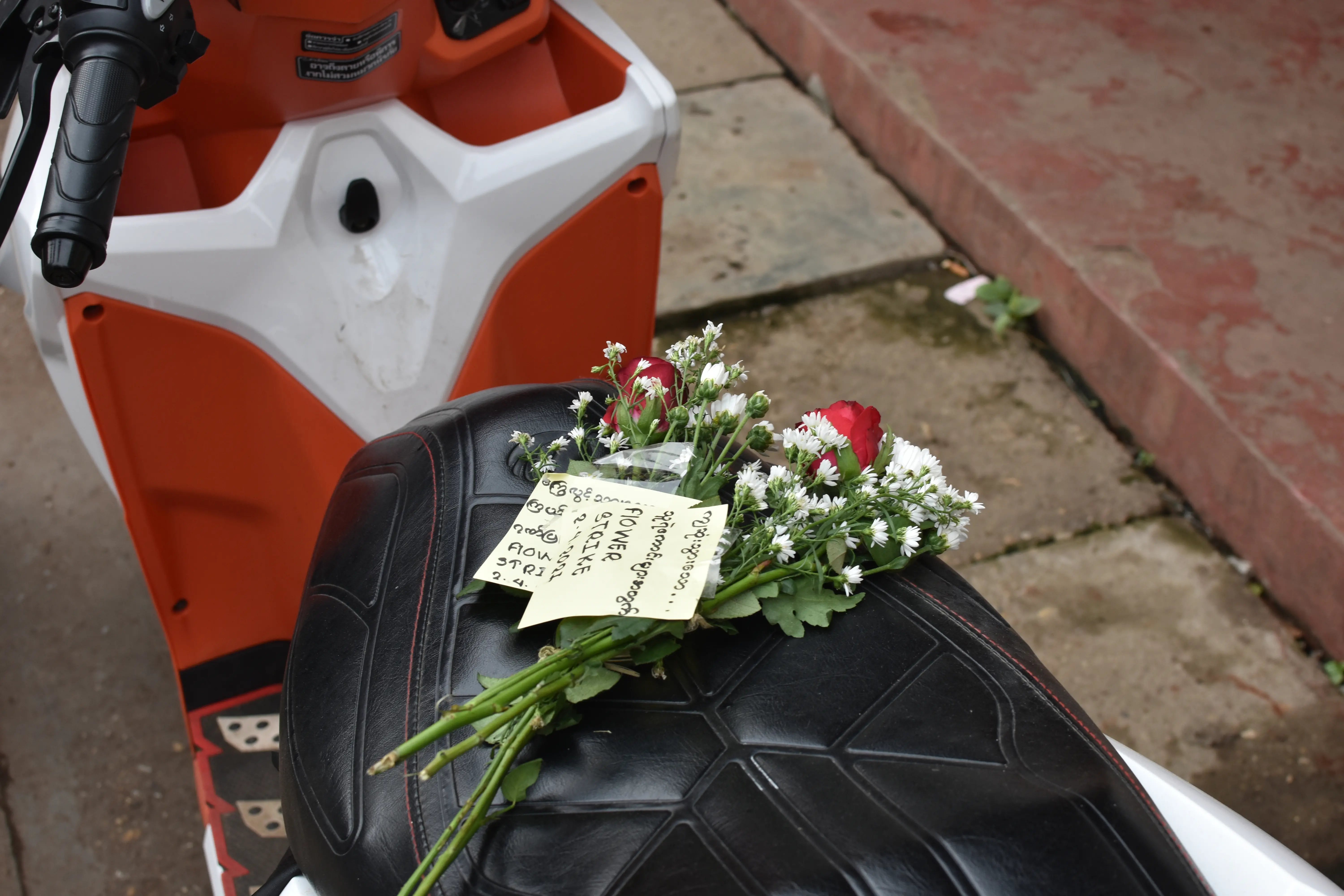 Flowers and notes sit on the seat of a parked motorbike.