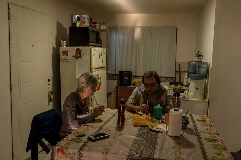 Parents of a victim sit at a dinner table in their home