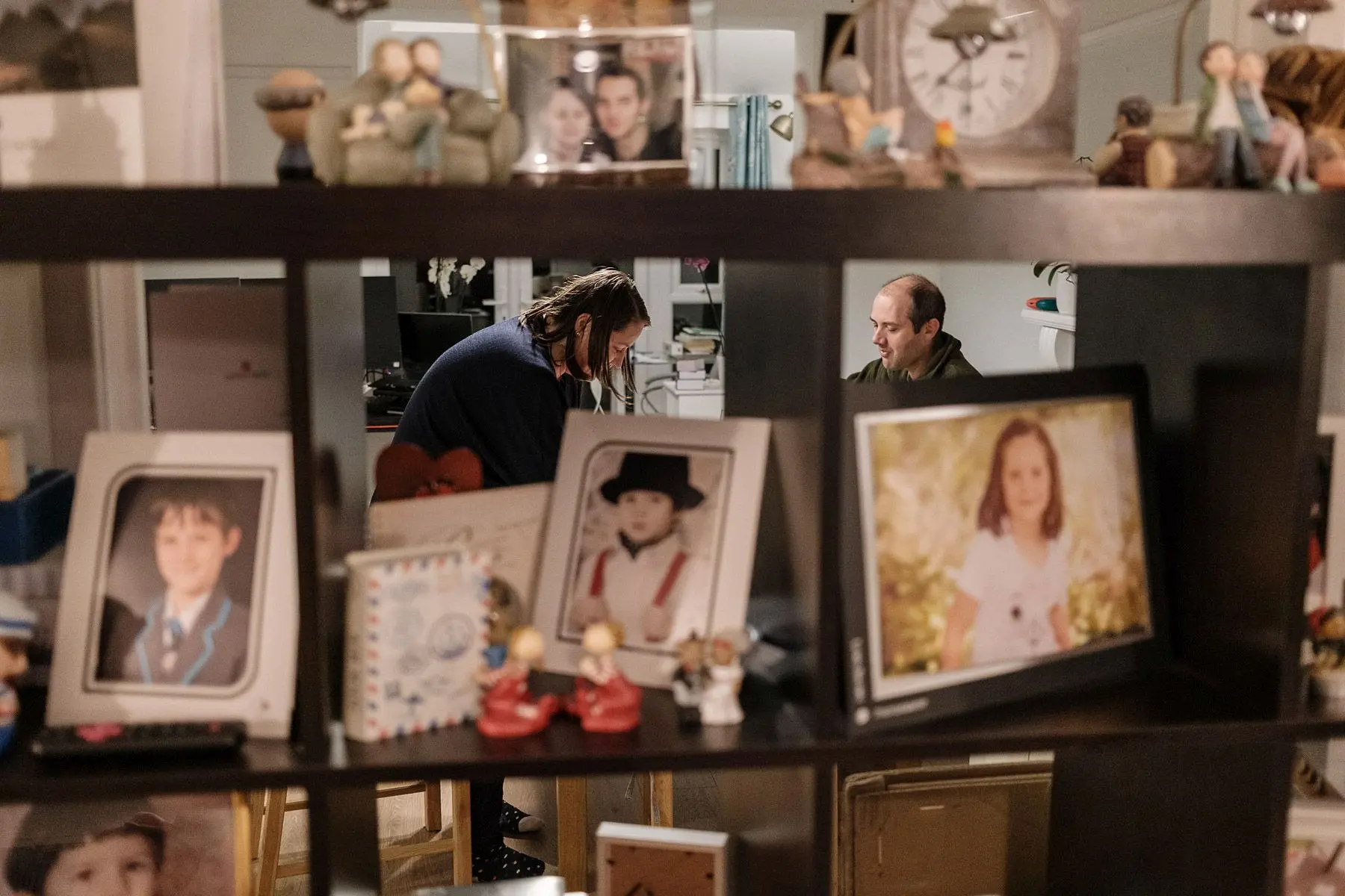 Surrounded by family pictures, a couple sits in their living room
