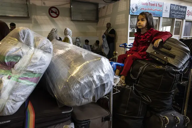 young girl sits atop luggage suitcases at airport