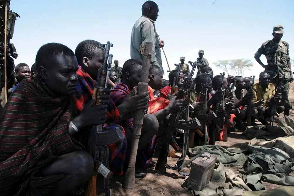 Young men sit with weapons