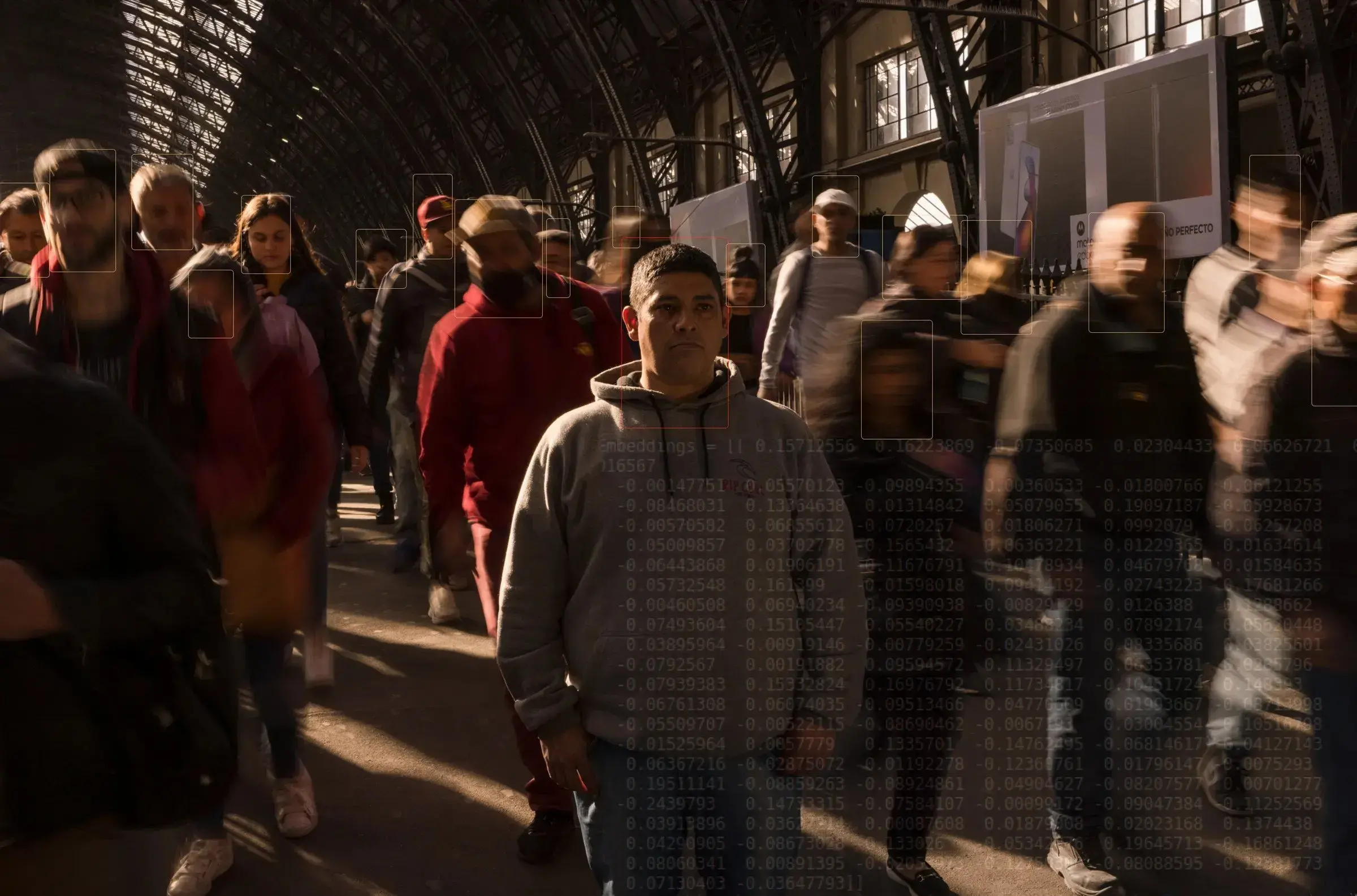 People stand in a crowd. Subtle white boxes are around their faces to suggest facial recognition monitoring.