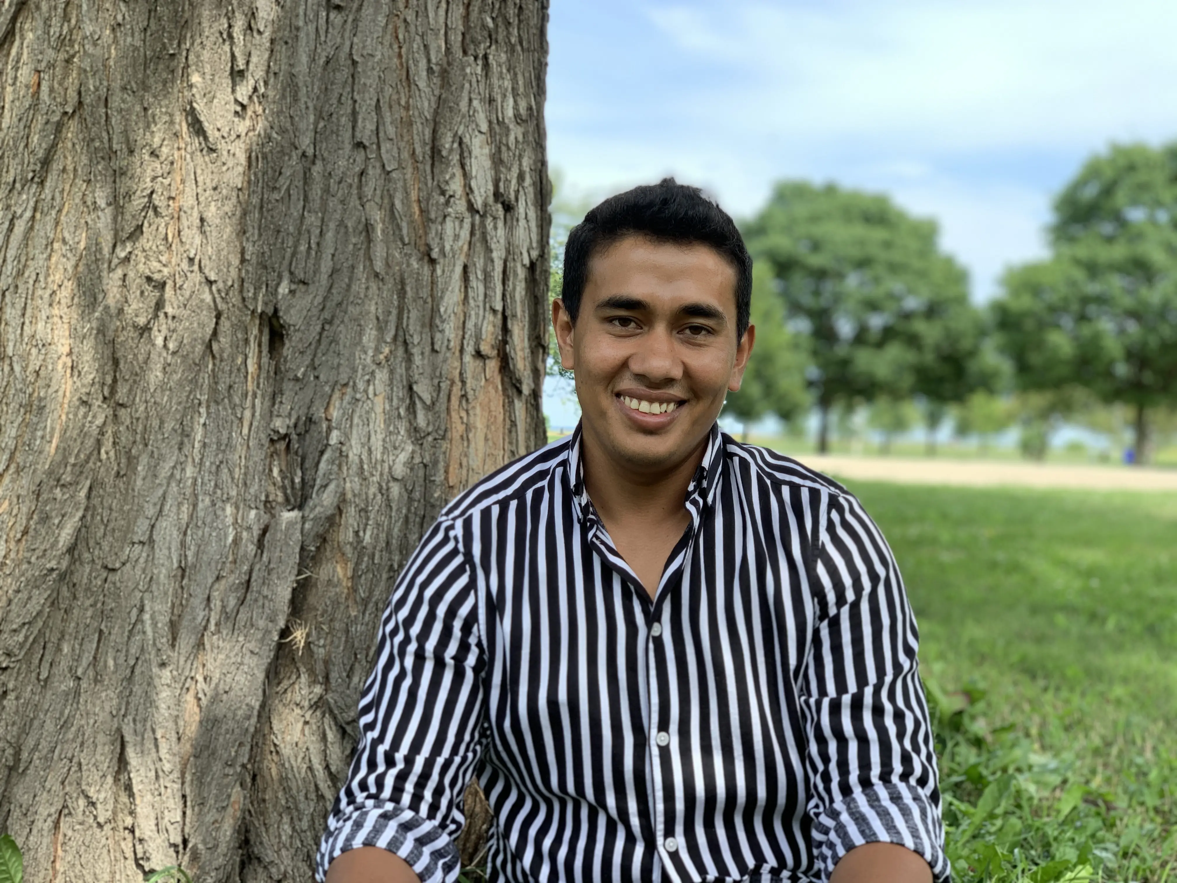 Man sits in front of tree 