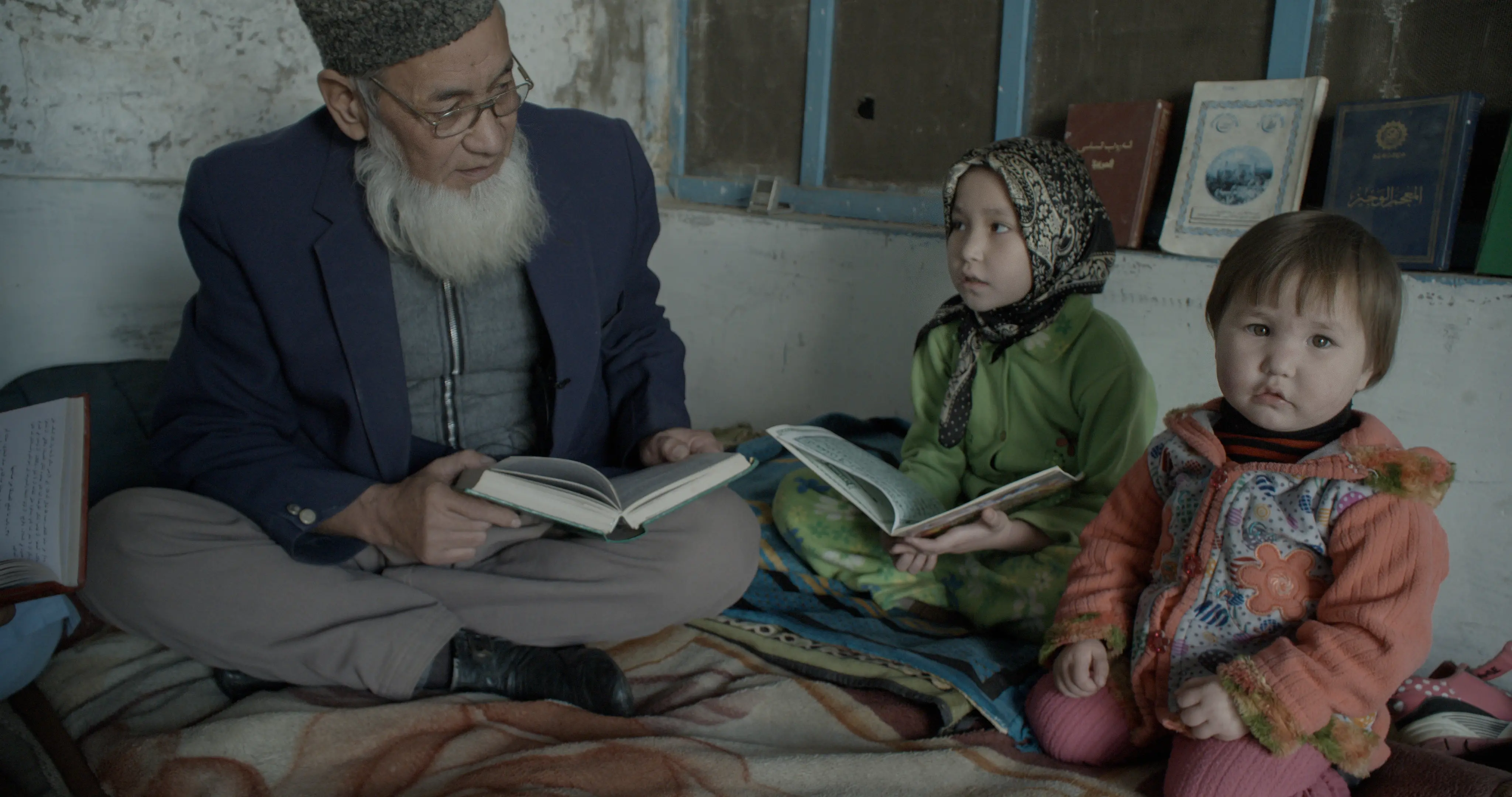Niaz Ghafoor and two children sit with books.
