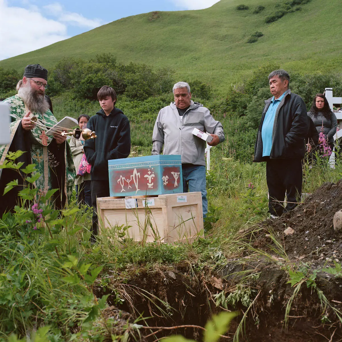 A priest reads over Anastasia's remains at a hillside burial site before she is interred.
