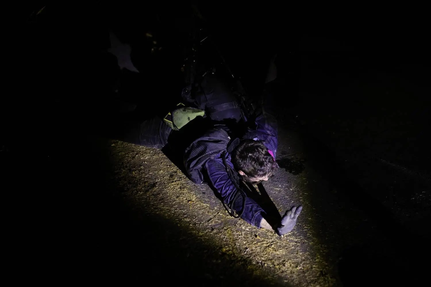 A protester reaches out while being arrested on a dark suburban street in Portland, Oregon.