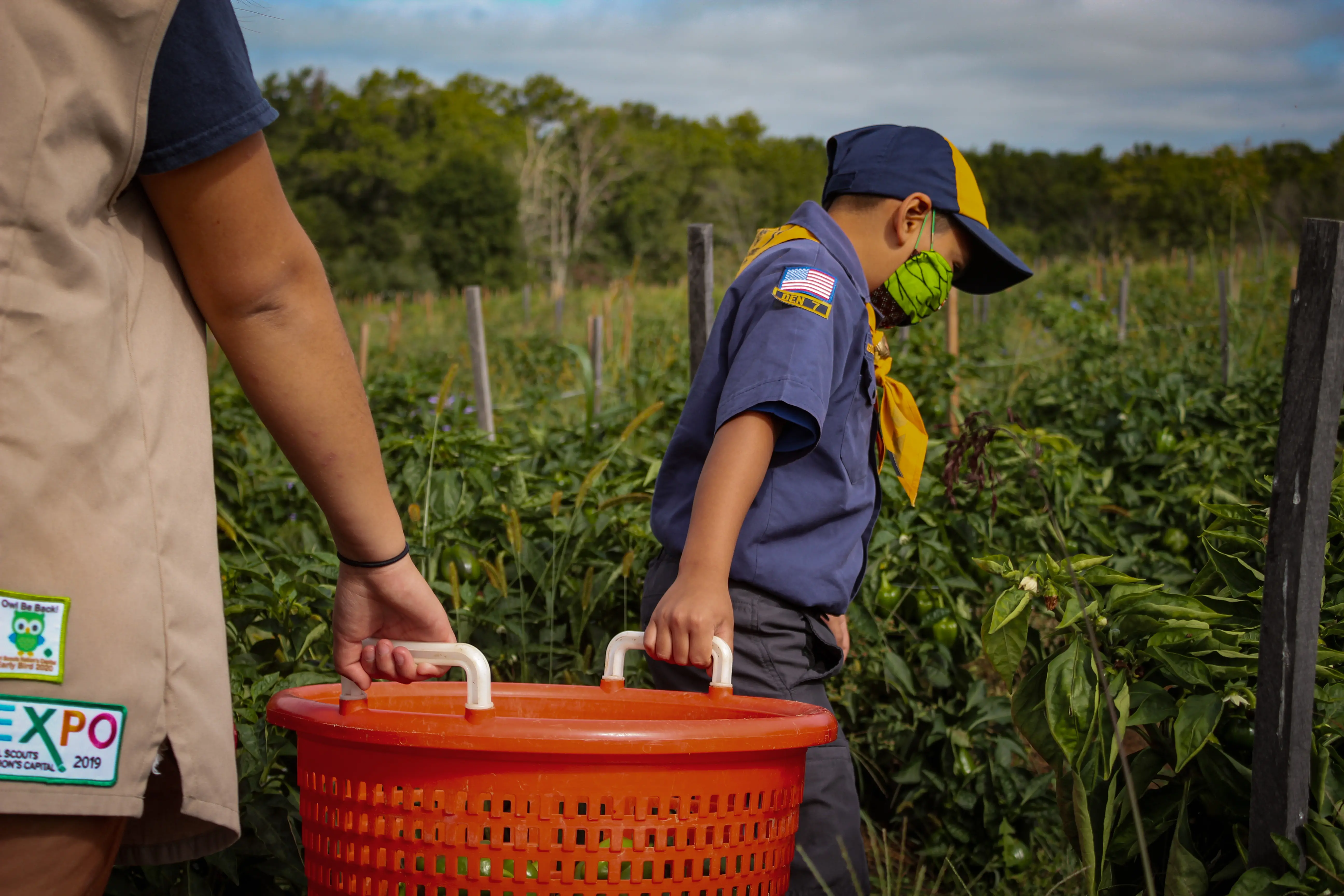 Two volunteers lift a basket at a farm.