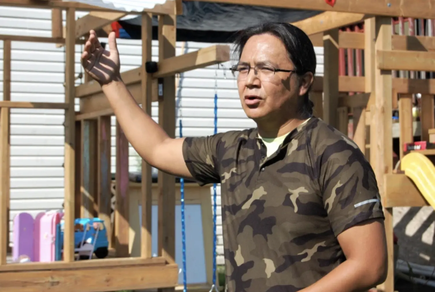 First nations member stands in front of home