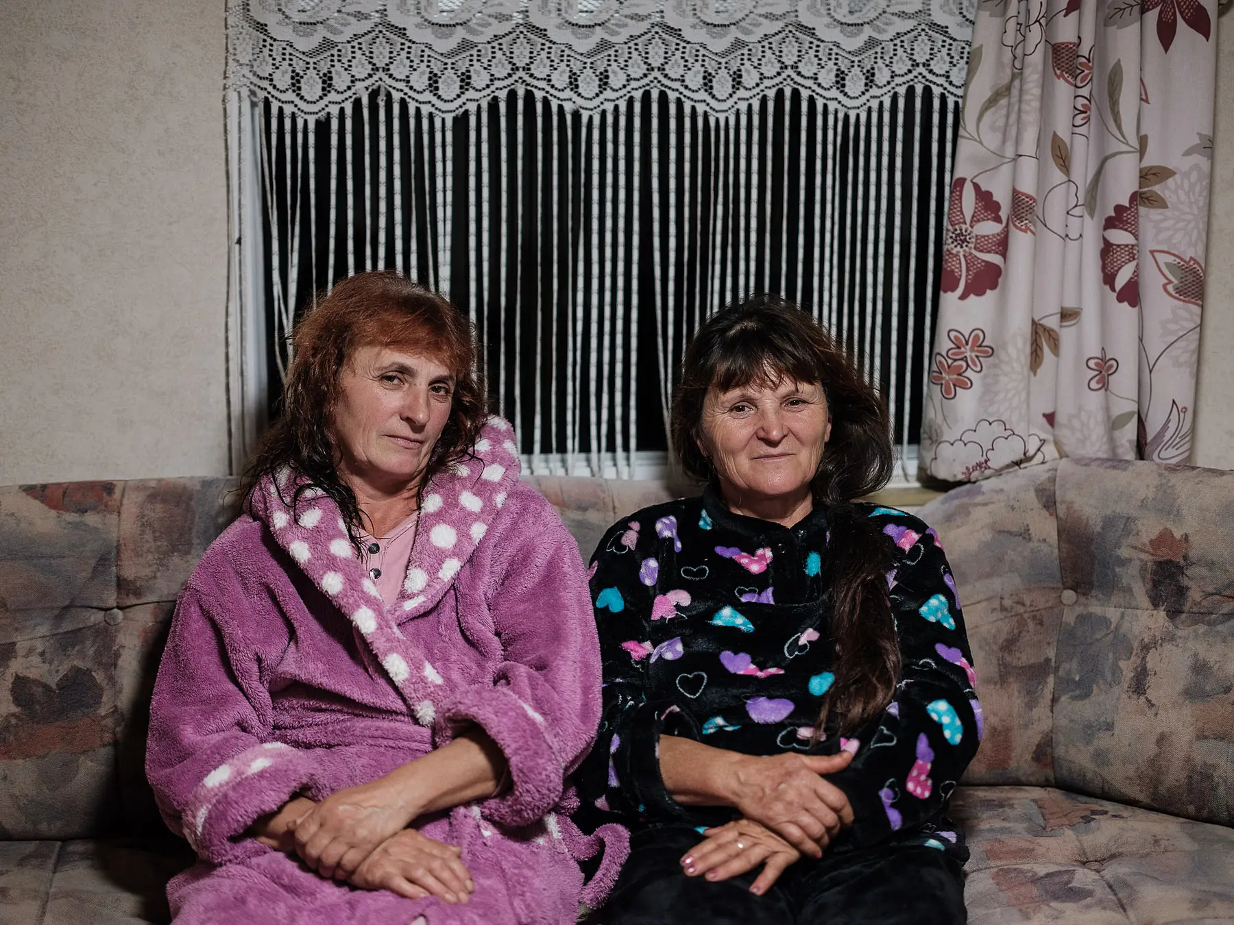 Two friends and seasonal workers sit together on a couch