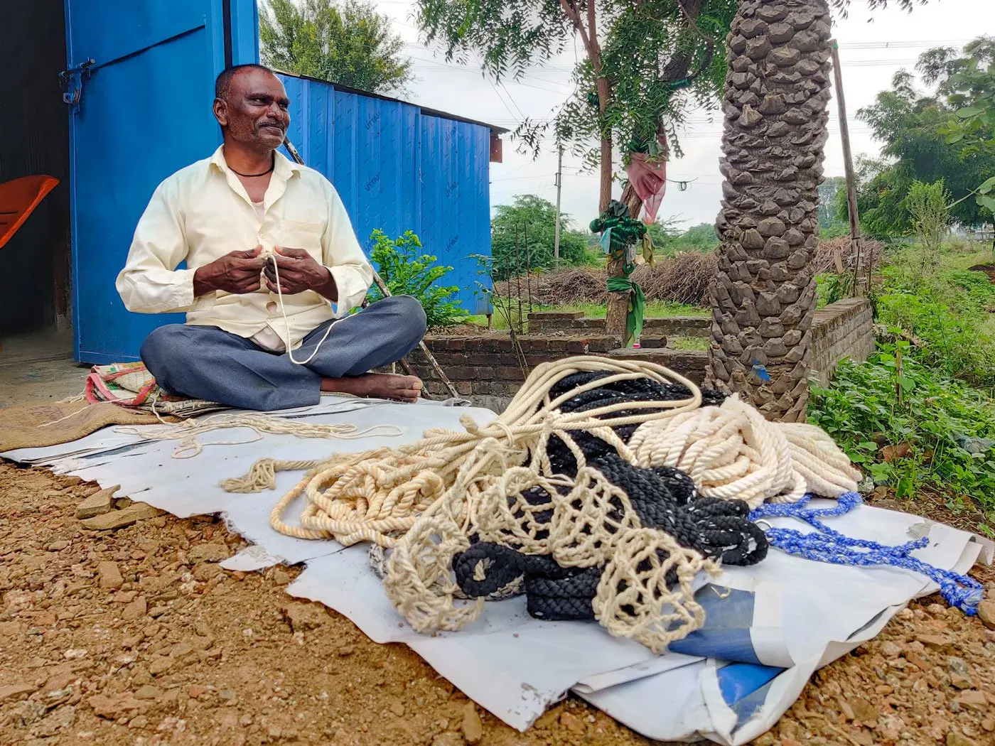Man sitting with ropes he typically sells at the market