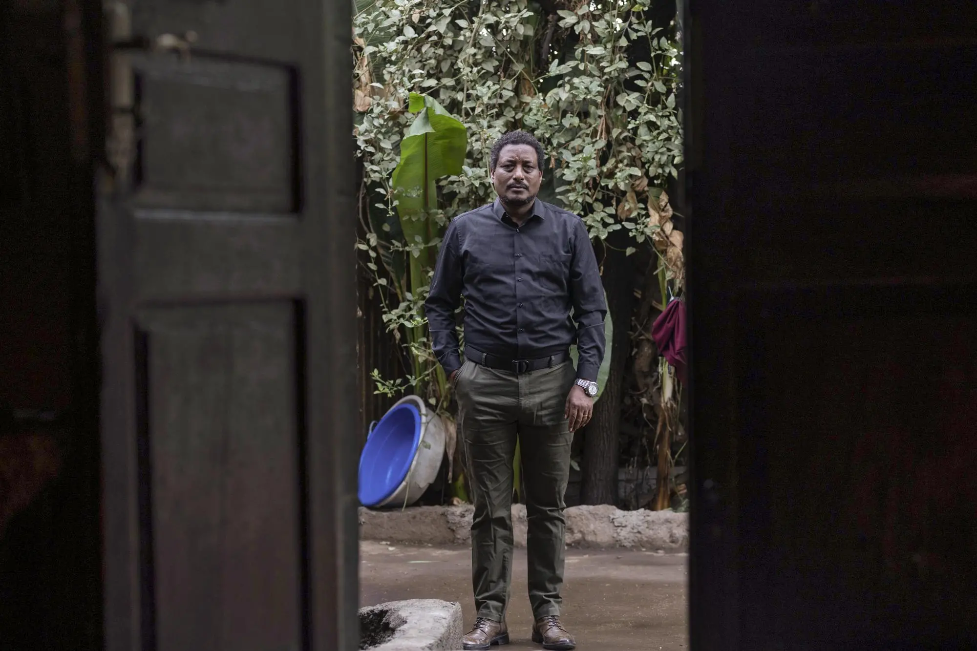 A man stands outside a doorway.