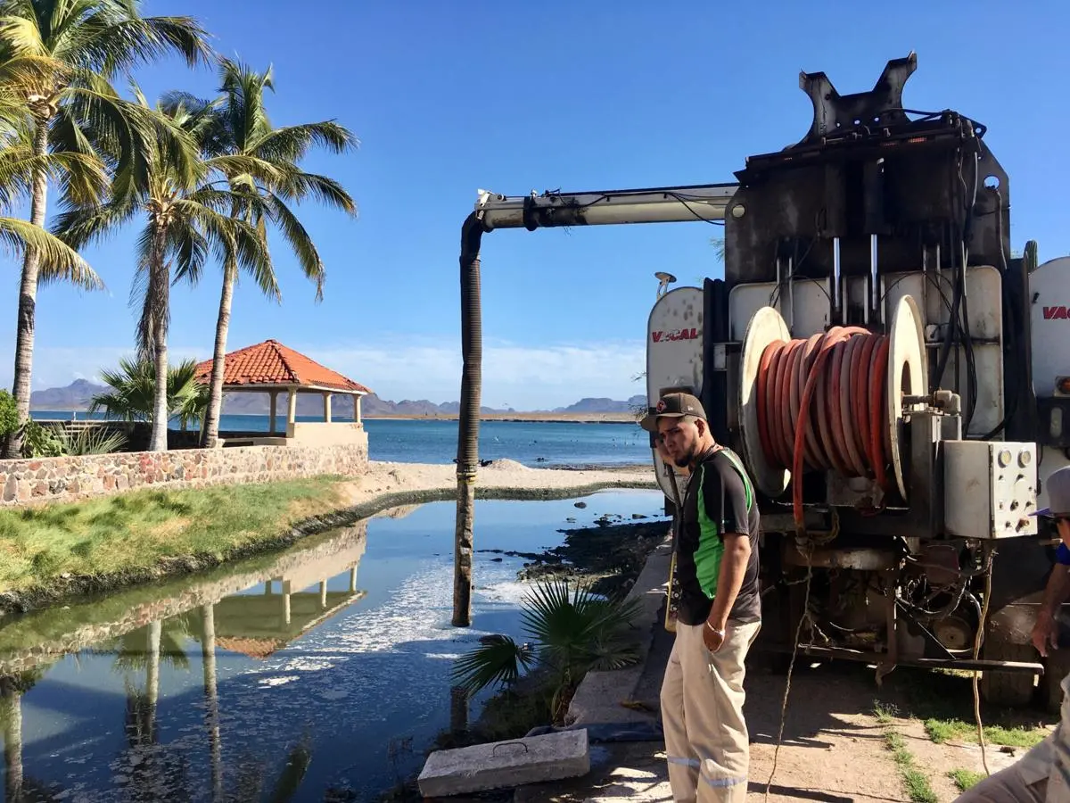 A worker looks at raw sewage flowing out a neighborhood