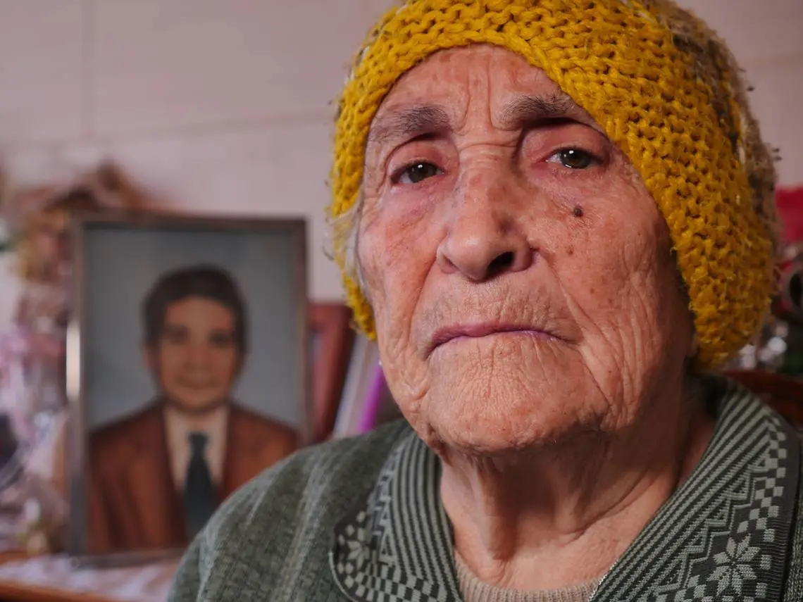 A woman sits in her home