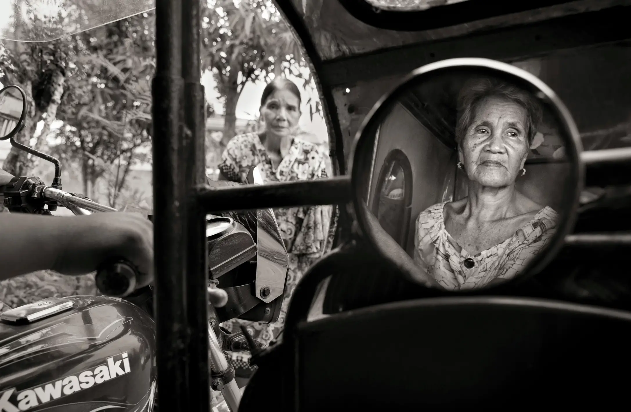 A woman's face is reflected through a motorcycle mirror