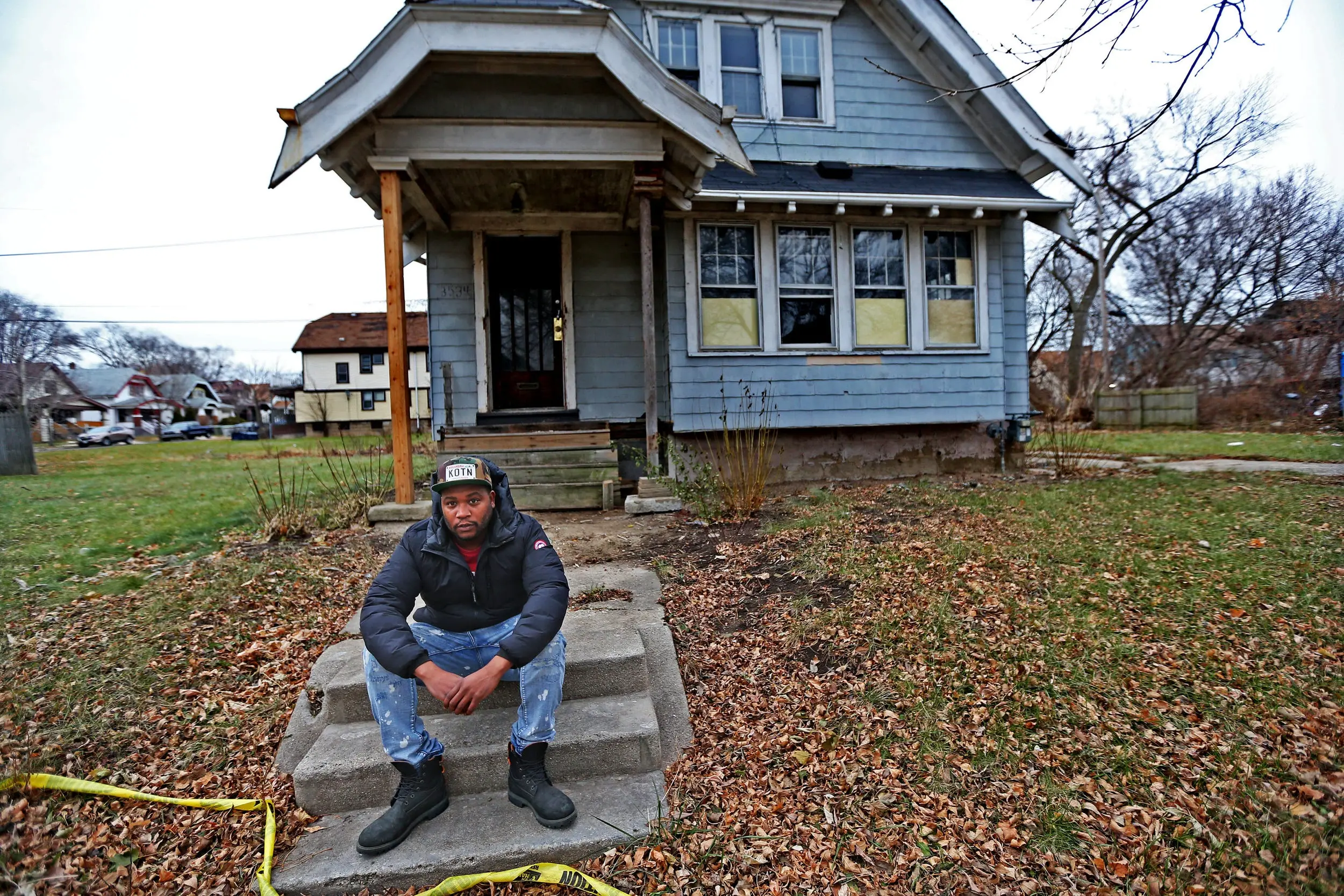 A man sits in front of a house