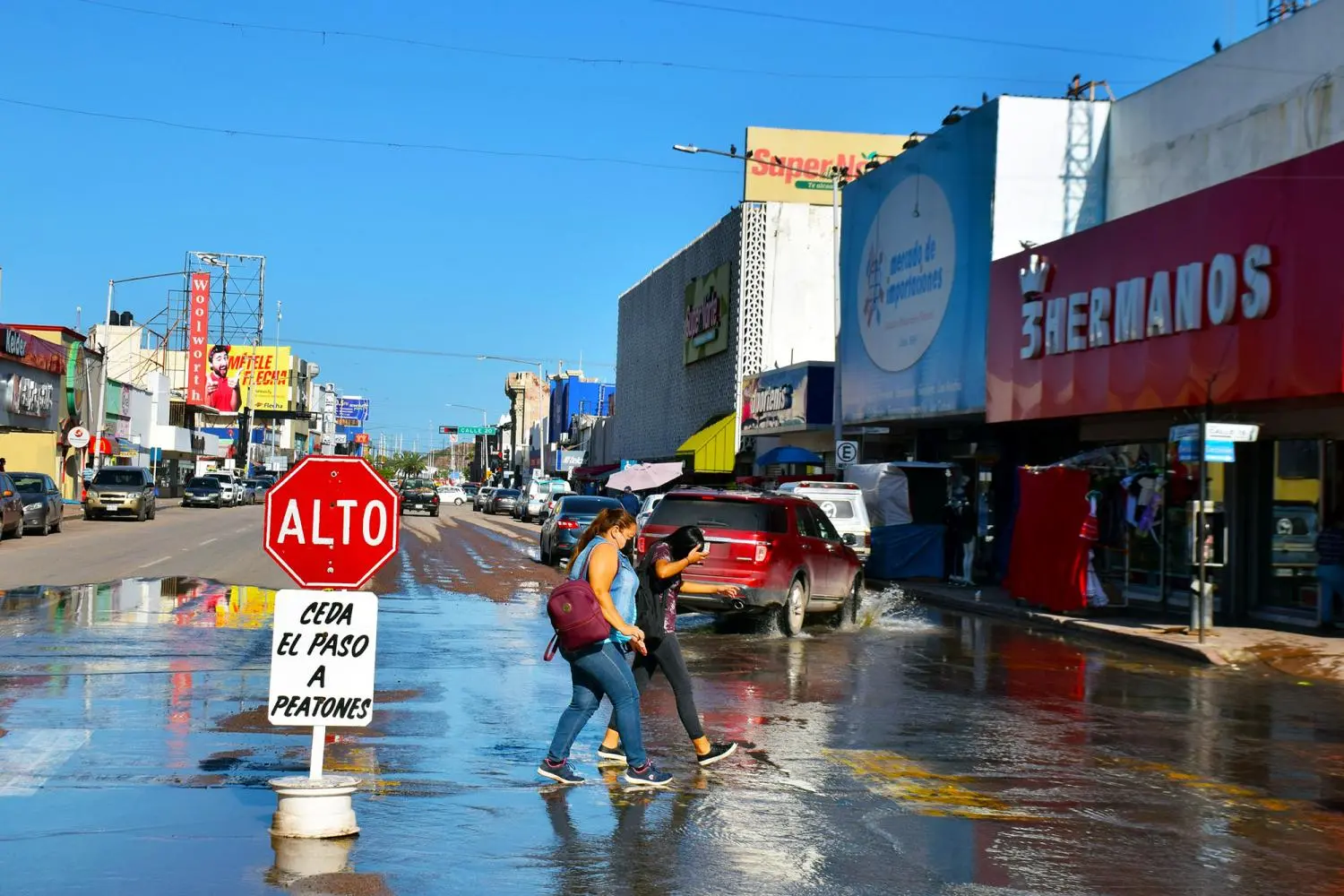 Two women navigating sewage water in town