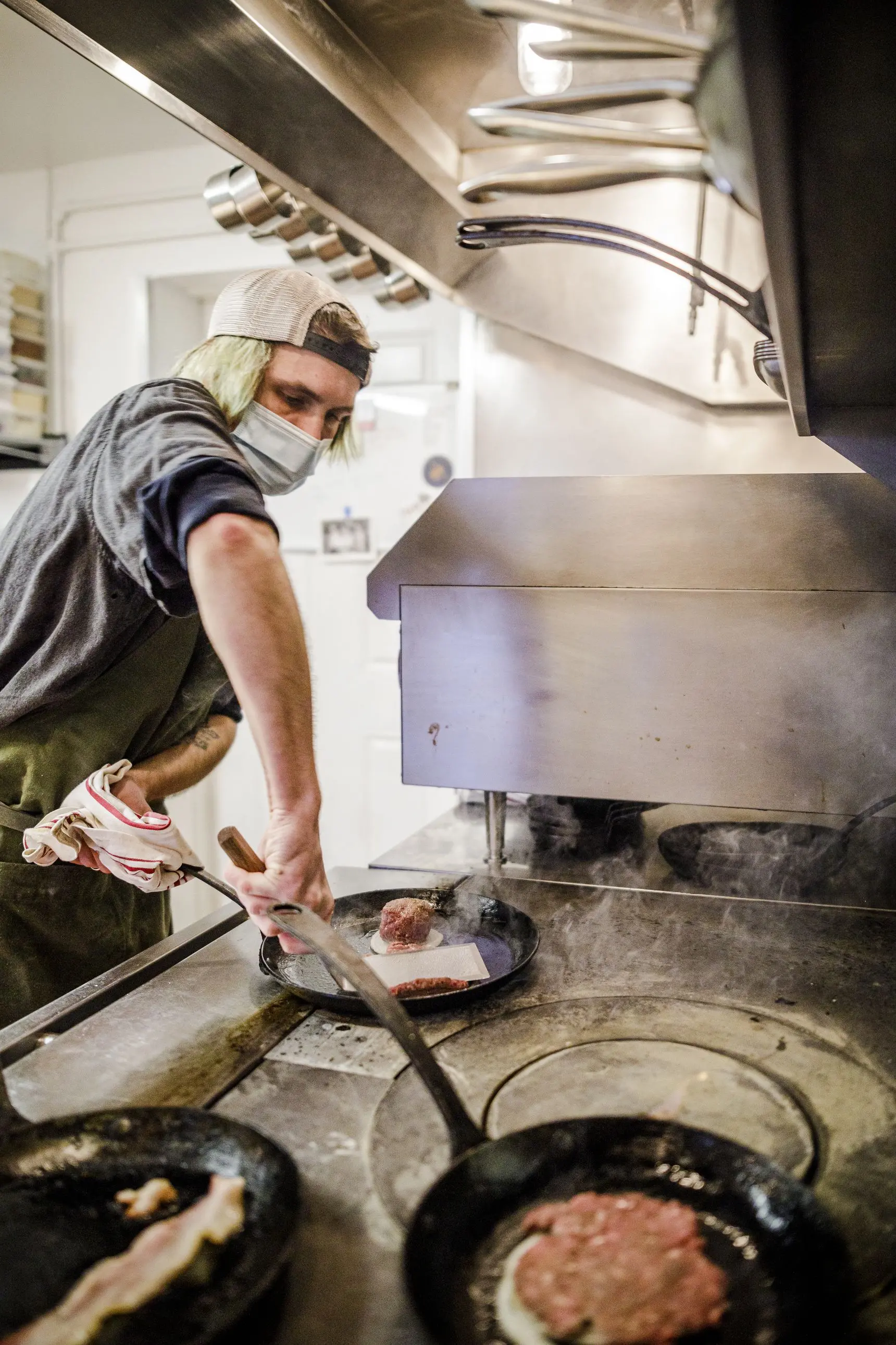 A cook prepares burgers on the grill