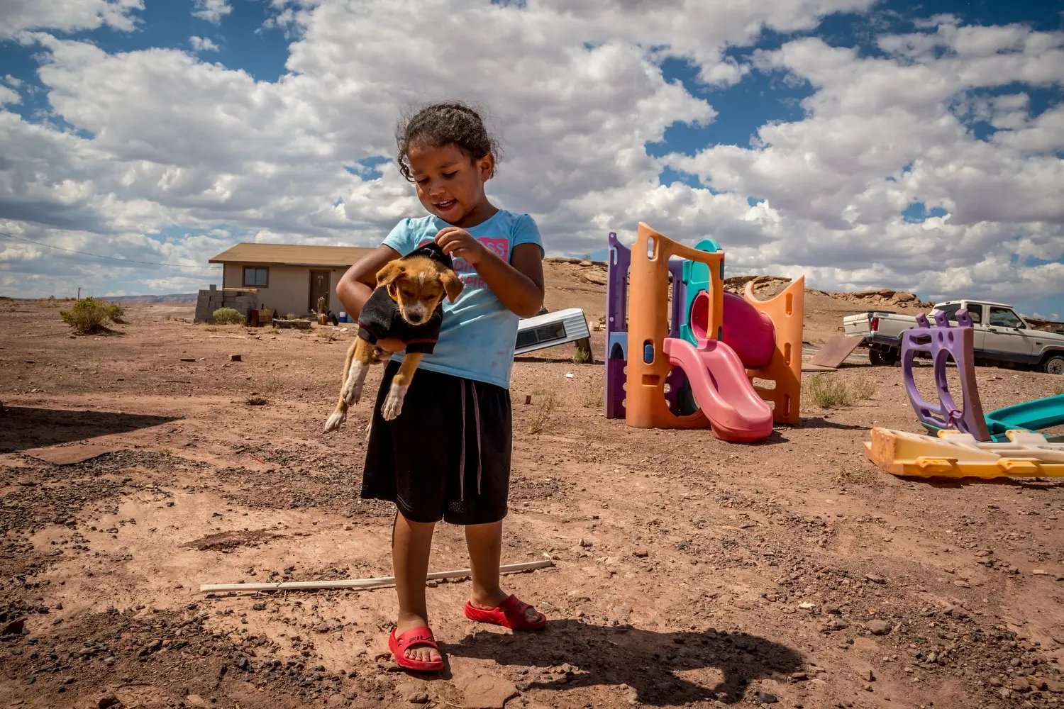Zoe Beard, holding a dog, plays in her yard. Image by Mary F. Calvert. United States, 2020.