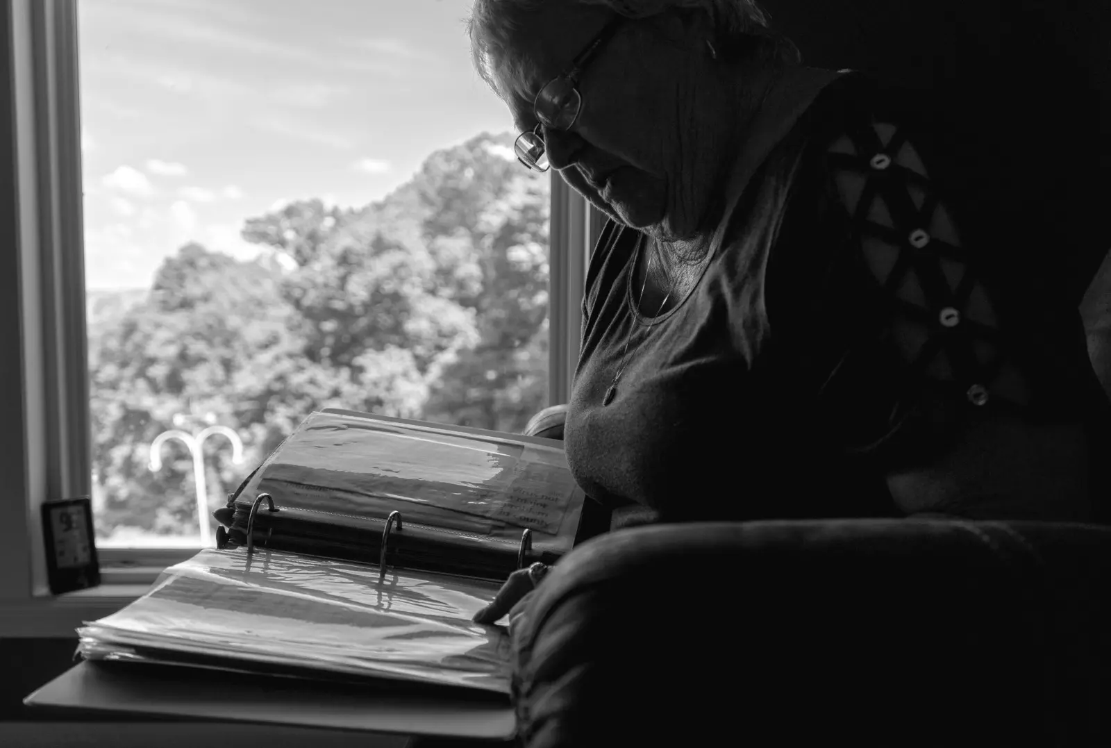 Nadine Garland sits in her living room and looks through a binder of old newspaper articles