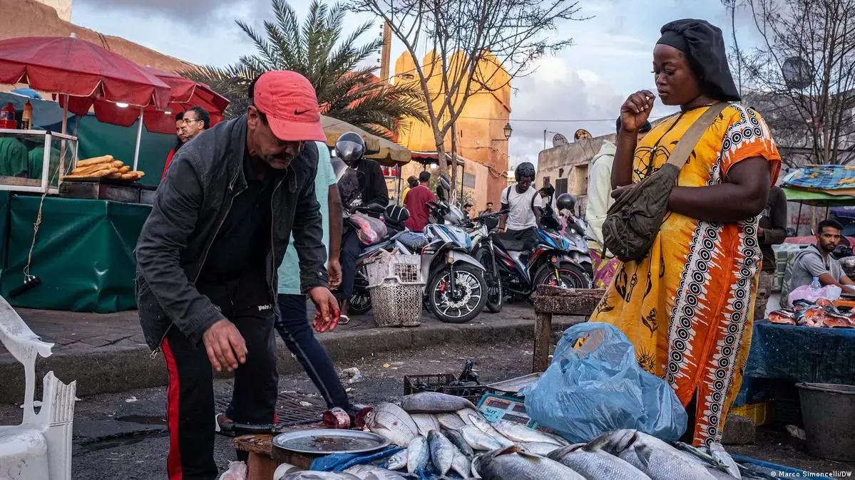 A Senegalese woman buys fish from a vendor in Casablanca's Medina market