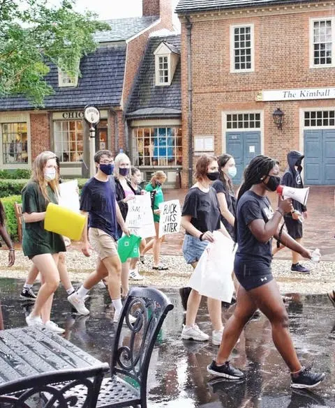 Students with posters walk down a street.