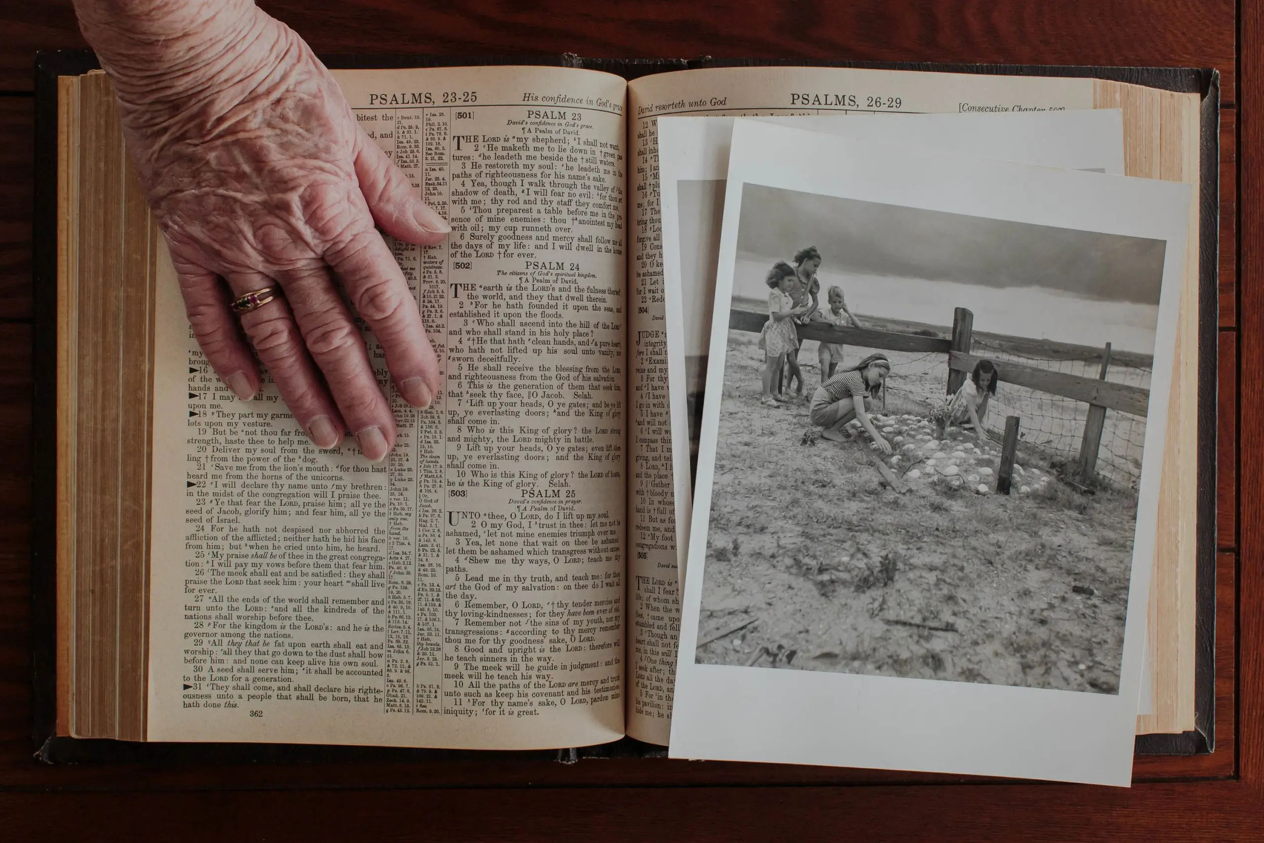 Woman places hand over old photographs and Bible