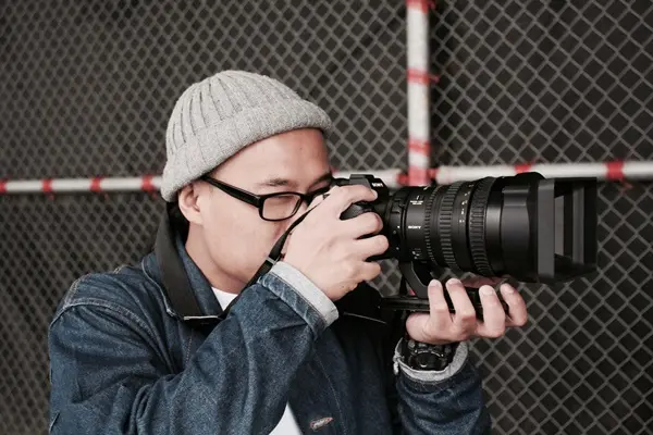 A man holds up a large DSLR camera to take a picture.