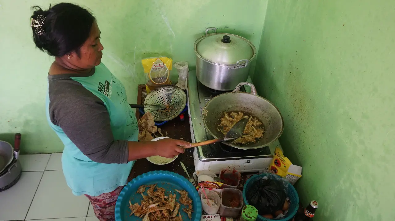 A woman stirs pot of fish