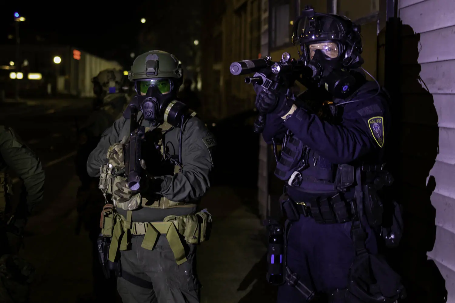 Federal Department of Homeland Security officers point "less-lethal" munitions weapons at a group of protesters demonstrating near the Immigration and Customs Enforcement building on the night of January 20, 2021.