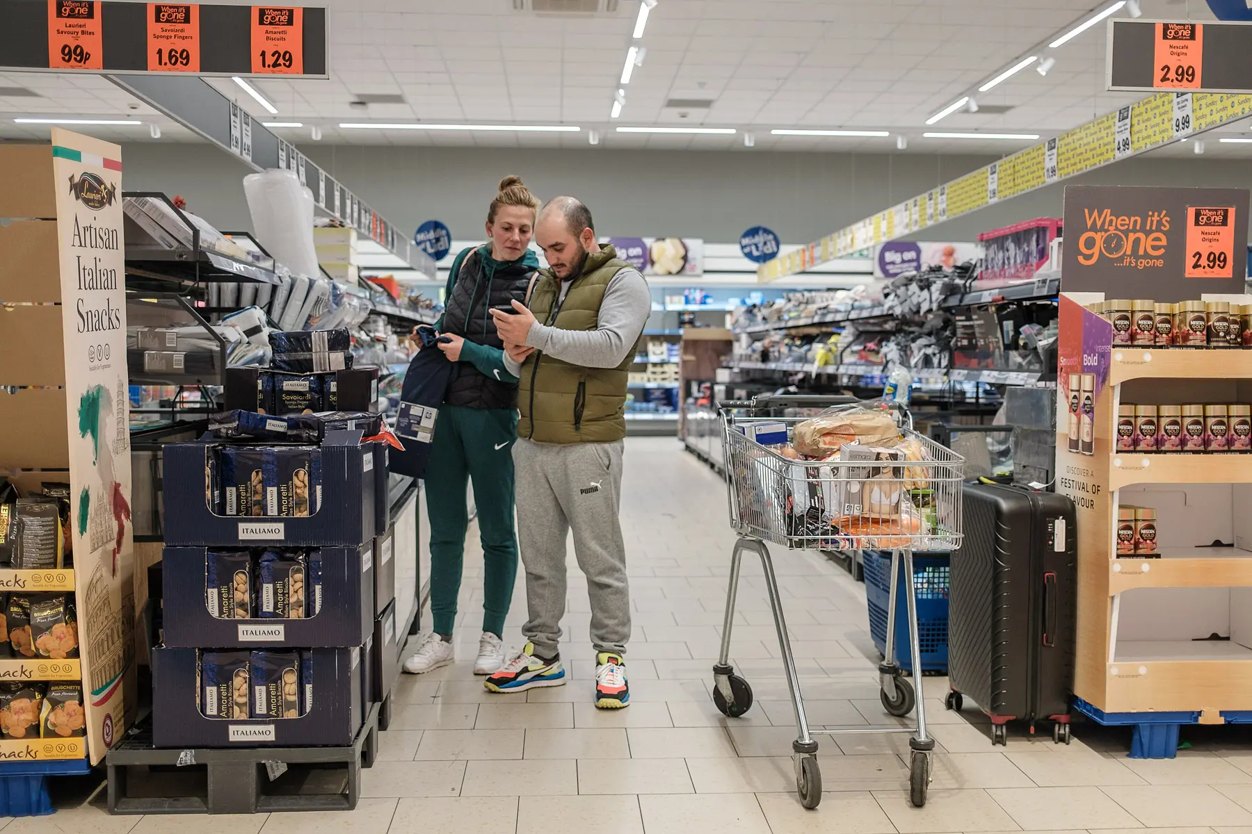 a couple shops at a grocery store with a full cart