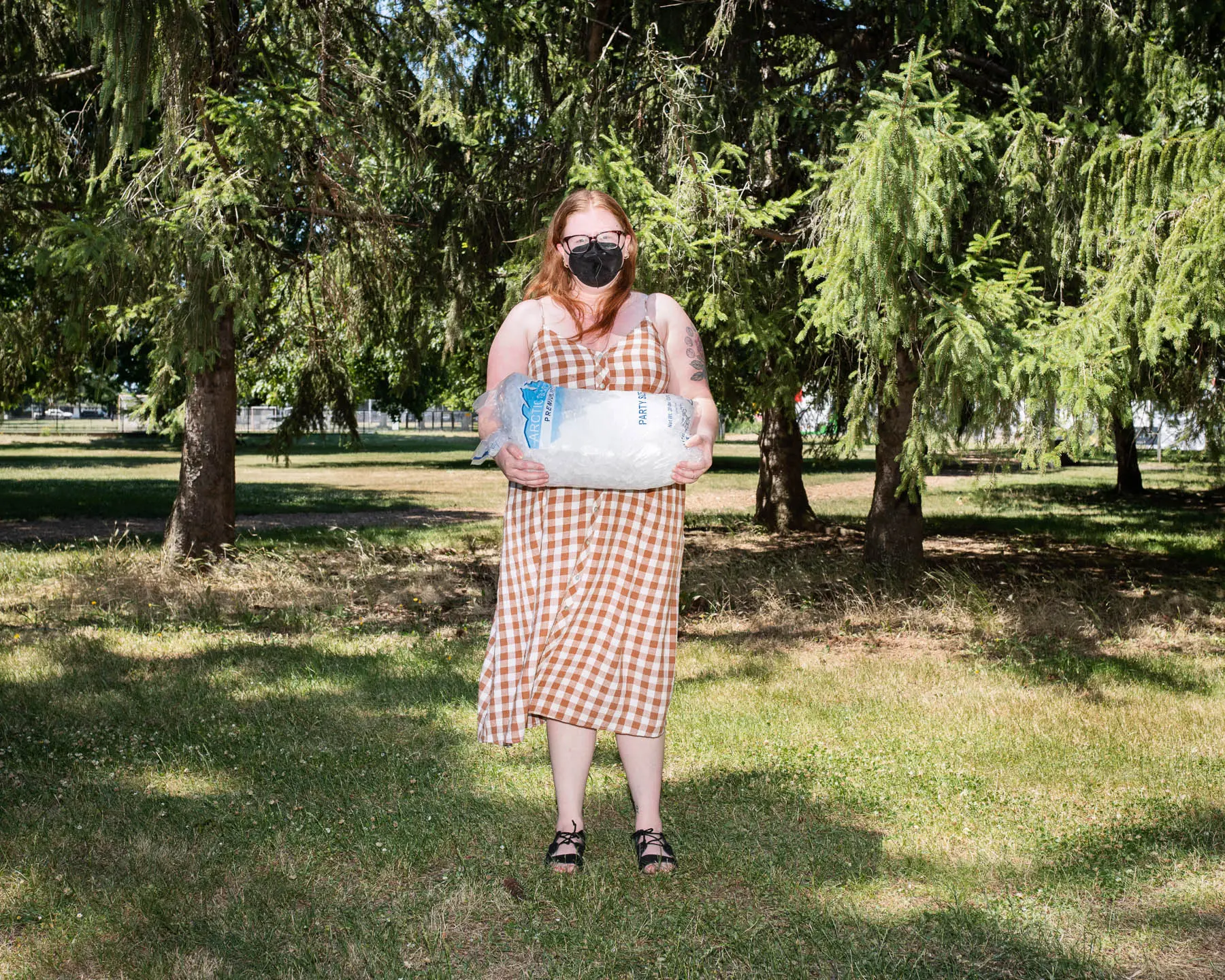 a woman stands in sundress holding ice