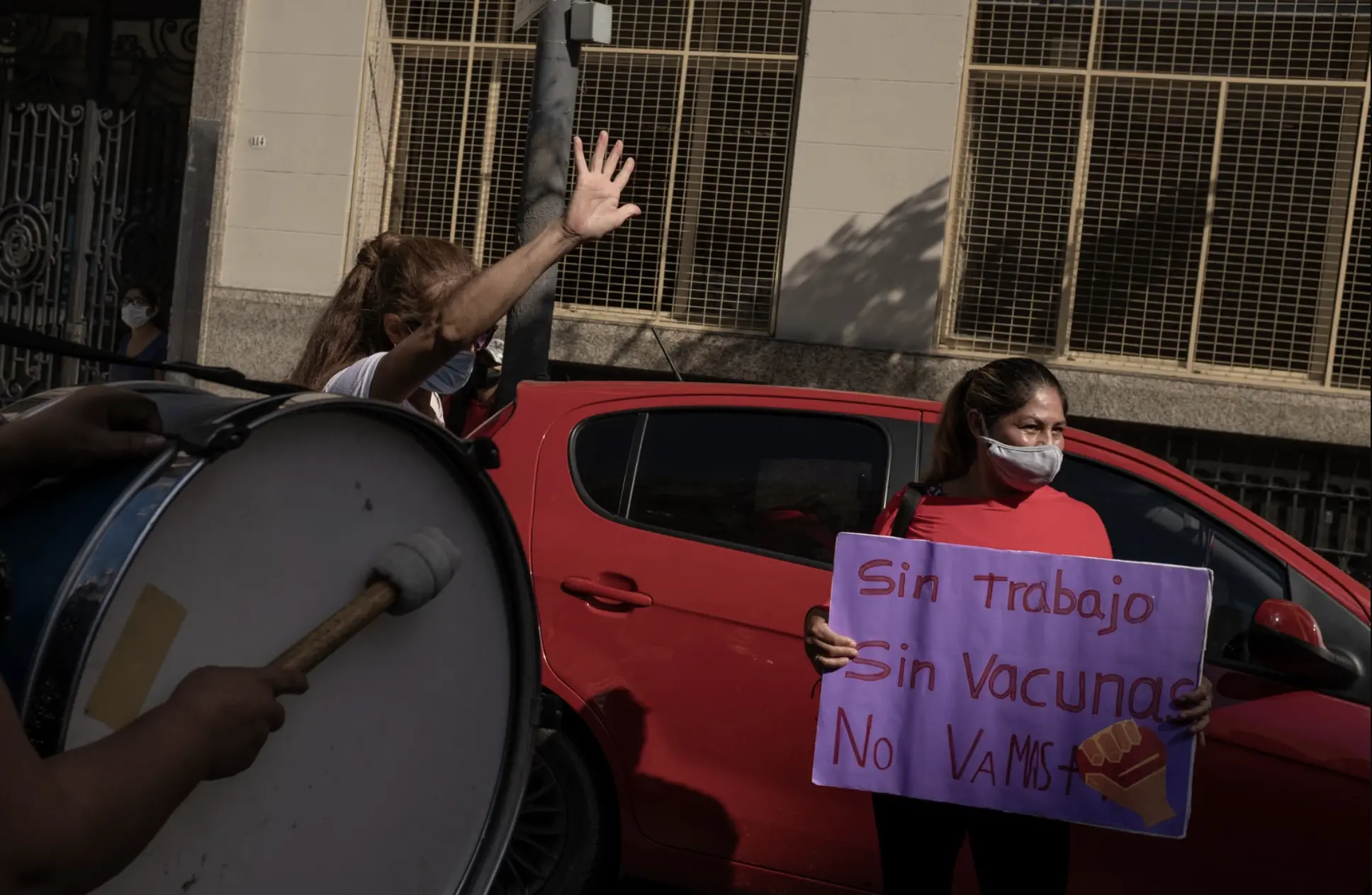 A woman holds drum and protest sign