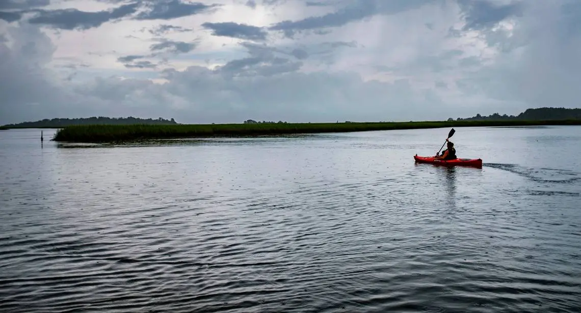 A kayaker paddles during low tide