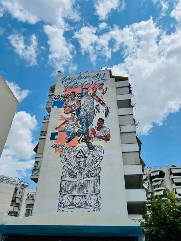 A mural of Giannis Antetokounmpo is displayed on the side of an apartment building