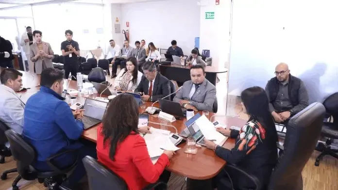 Assembly members sit at a table.