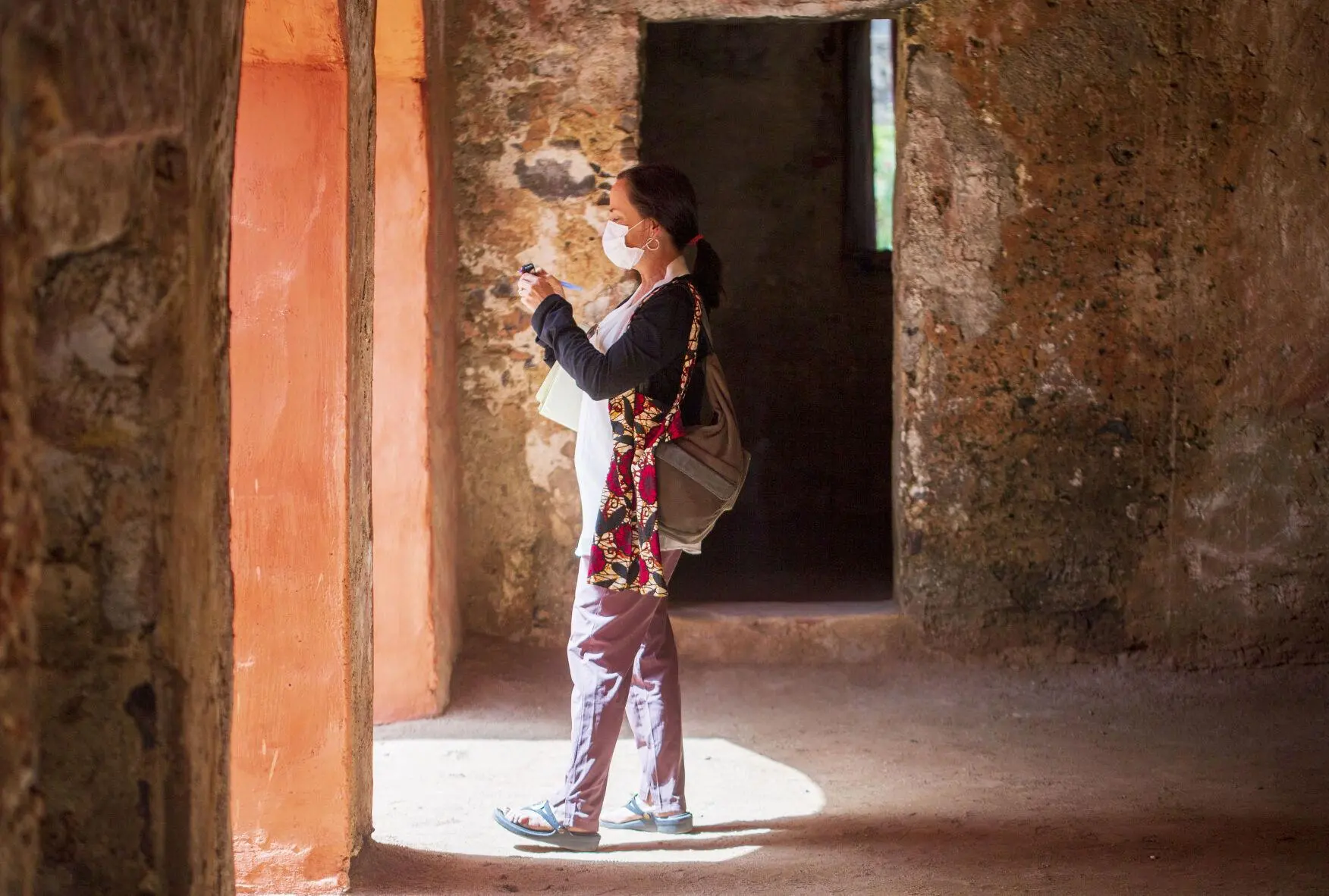 Jennifer Berry Hawes, wearing a medical face mask, takes a photo near a doorway.