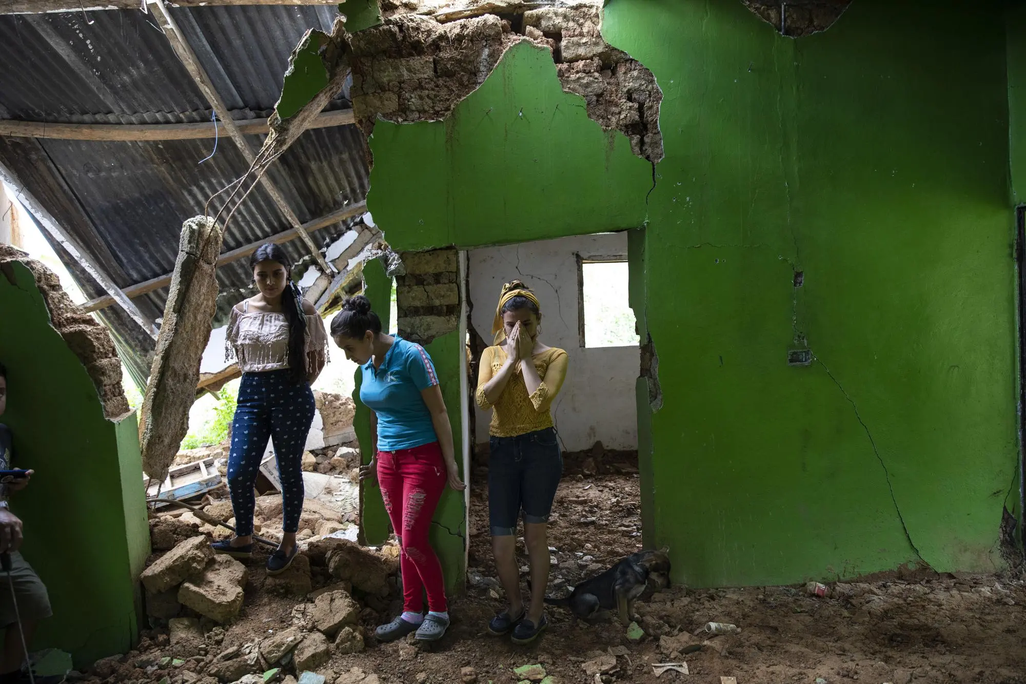 Women stand in their home after it was destroyed by landslide